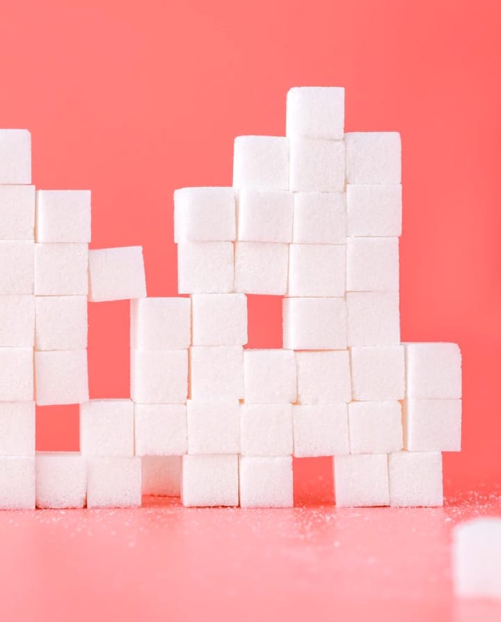 Picture of sugar cubes stacked on one another with a pink background